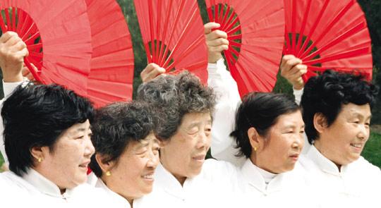 Women perform with fans during a ceremony in a park in Beijing, yesterday.